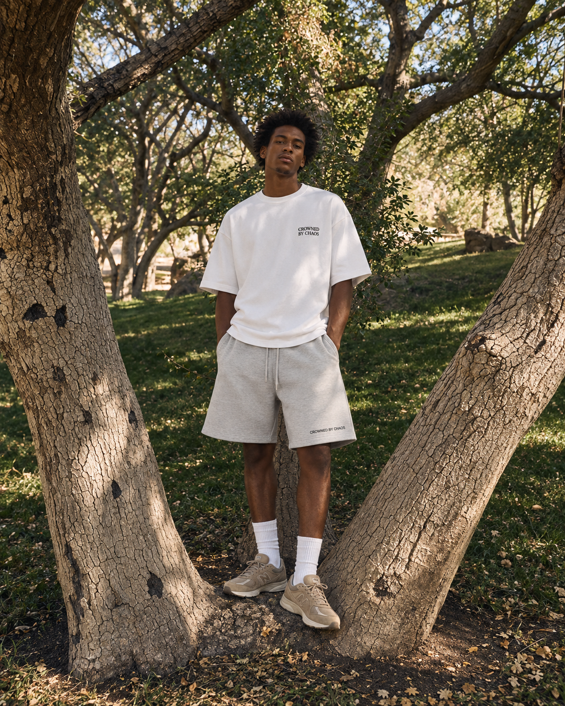 Mannequin portant un T-shirt blanc et un short gris CROWNED BY CHAOS dans un décor naturel