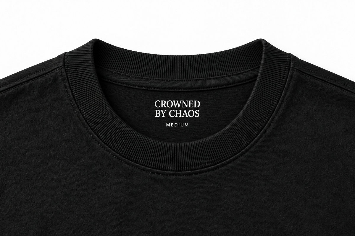 Détail du col côtelé et du marquage intérieur CROWNED BY CHAOS du T-shirt noir