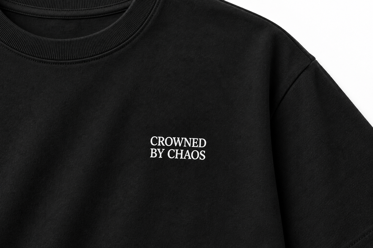 Détail du wordmark blanc CROWNED BY CHAOS sur le T-shirt noir