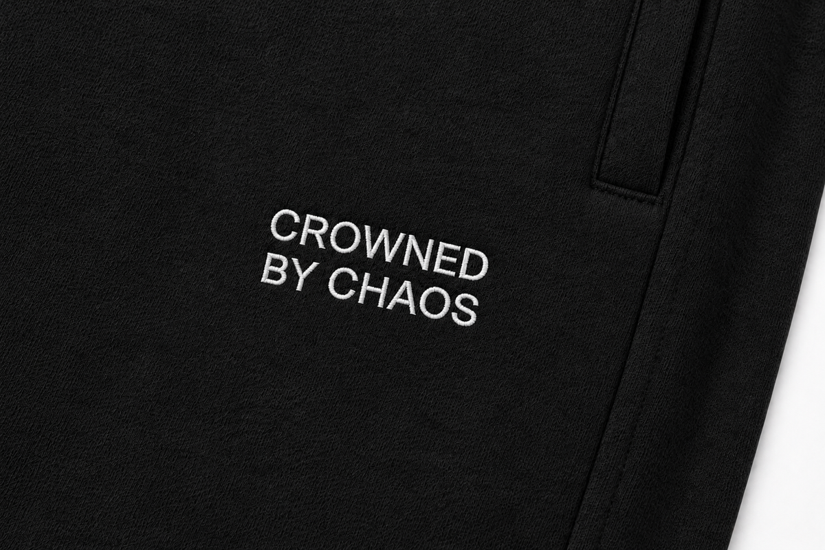 Détail du wordmark CROWNED BY CHAOS sur le pantalon noir