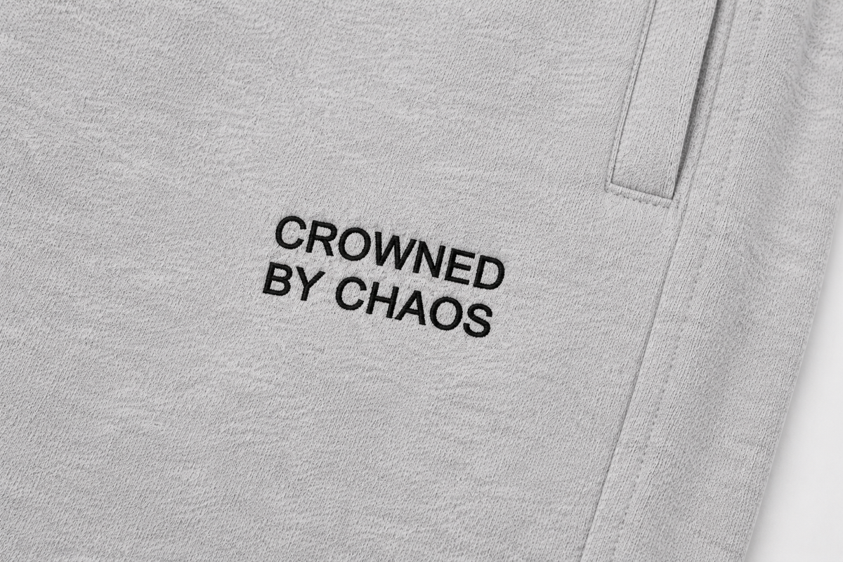 Détail du wordmark CROWNED BY CHAOS sur le pantalon gris chiné